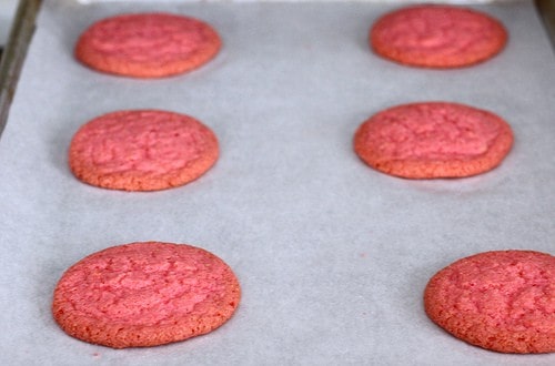 Pink gluten-free sugar cookies on a baking sheet.
