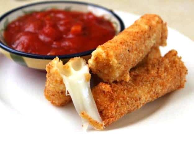 Gluten-Free Mozzarella Sticks on plate with bowl of marinara sauce.