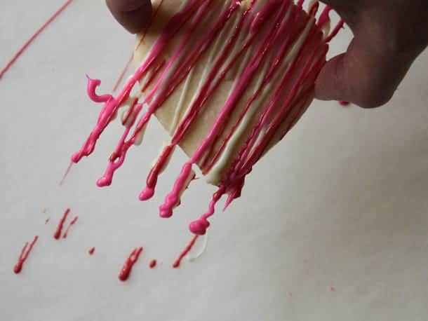Lifting decorated gluten-free cookie off a parchment sheet.