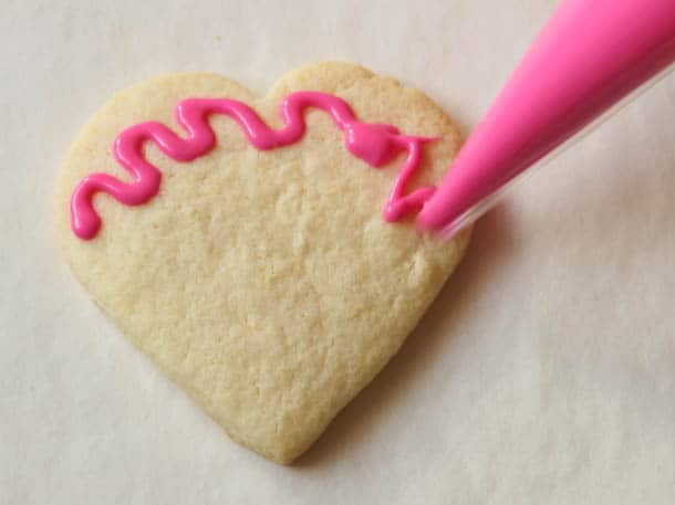Gluten-free sugar cookie hearts frosted with pink squiggle frosting.