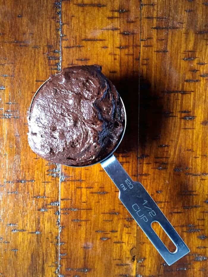 Gluten-free brownie batter in 1/2 cup measuring cup.