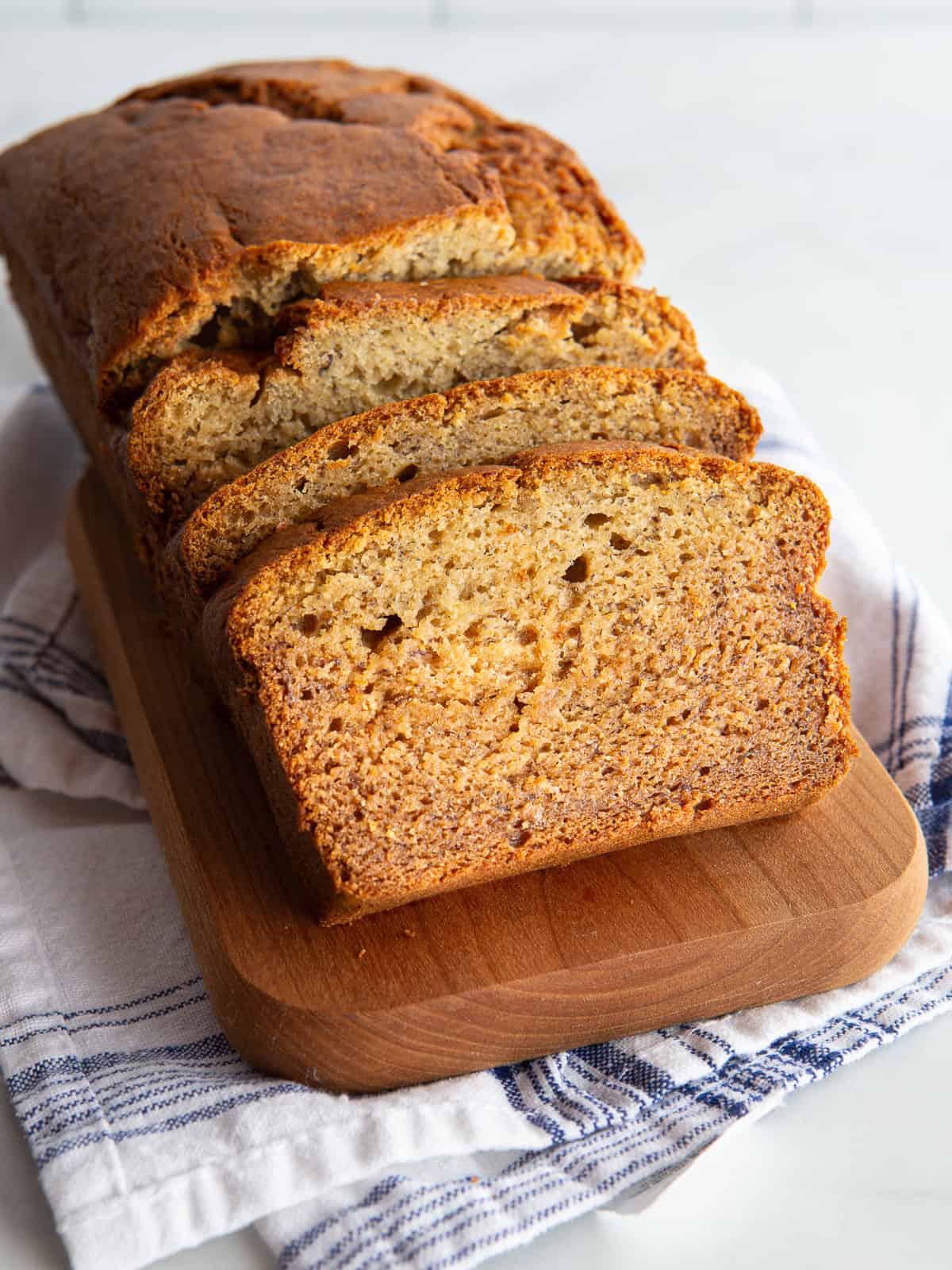 Gluten-free banana bread sliced on a wood cutting board.