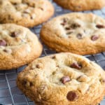 Large gluten-free chocolate chip cookies sitting on a cooling rack.